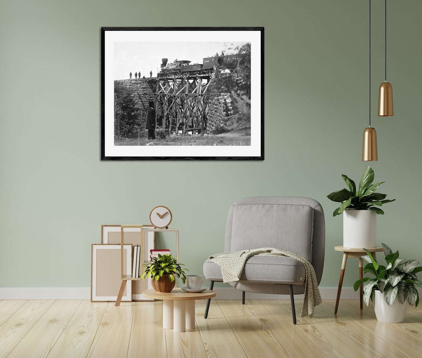 A framed paper print reproduction of a vintage photograph of a railroad bridge hanging on a green wall