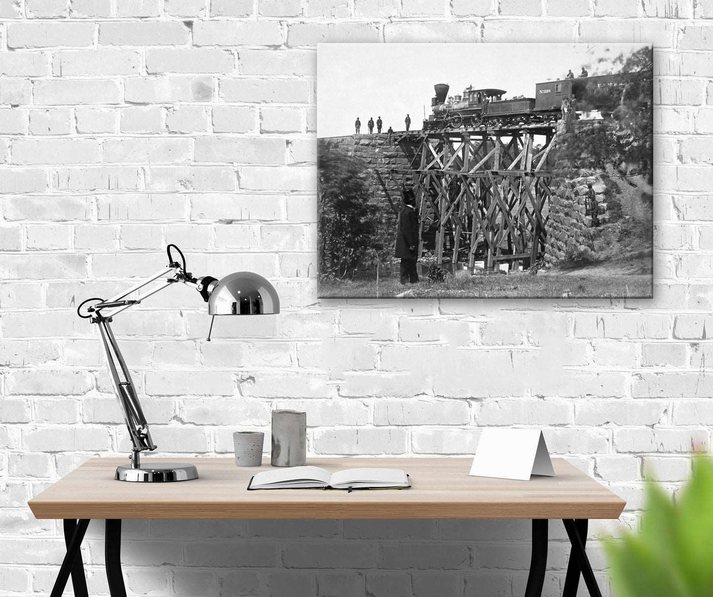 A canvas print of a vintage photograph hanging on a white brick wall above a desk