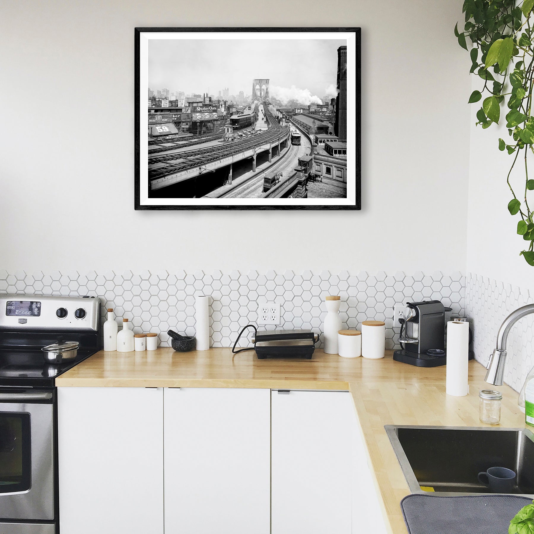 A photograph of a kitchen featuring a digital rendering of a framed paper print reproduction of a photograph of the Brooklyn Railroad Terminal