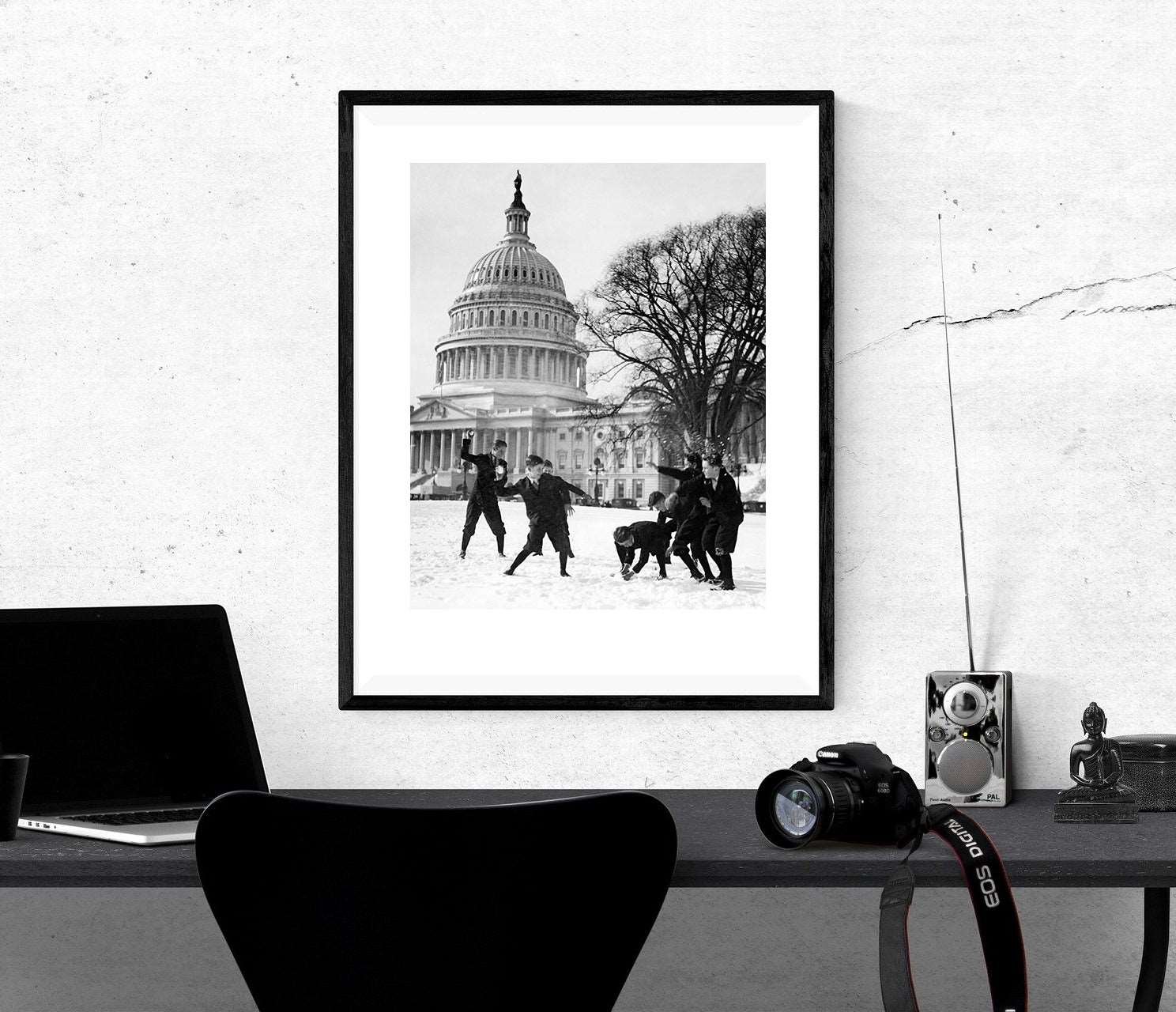 A framed print of a vintage photograph of Capitol Pages hangs above a black desk