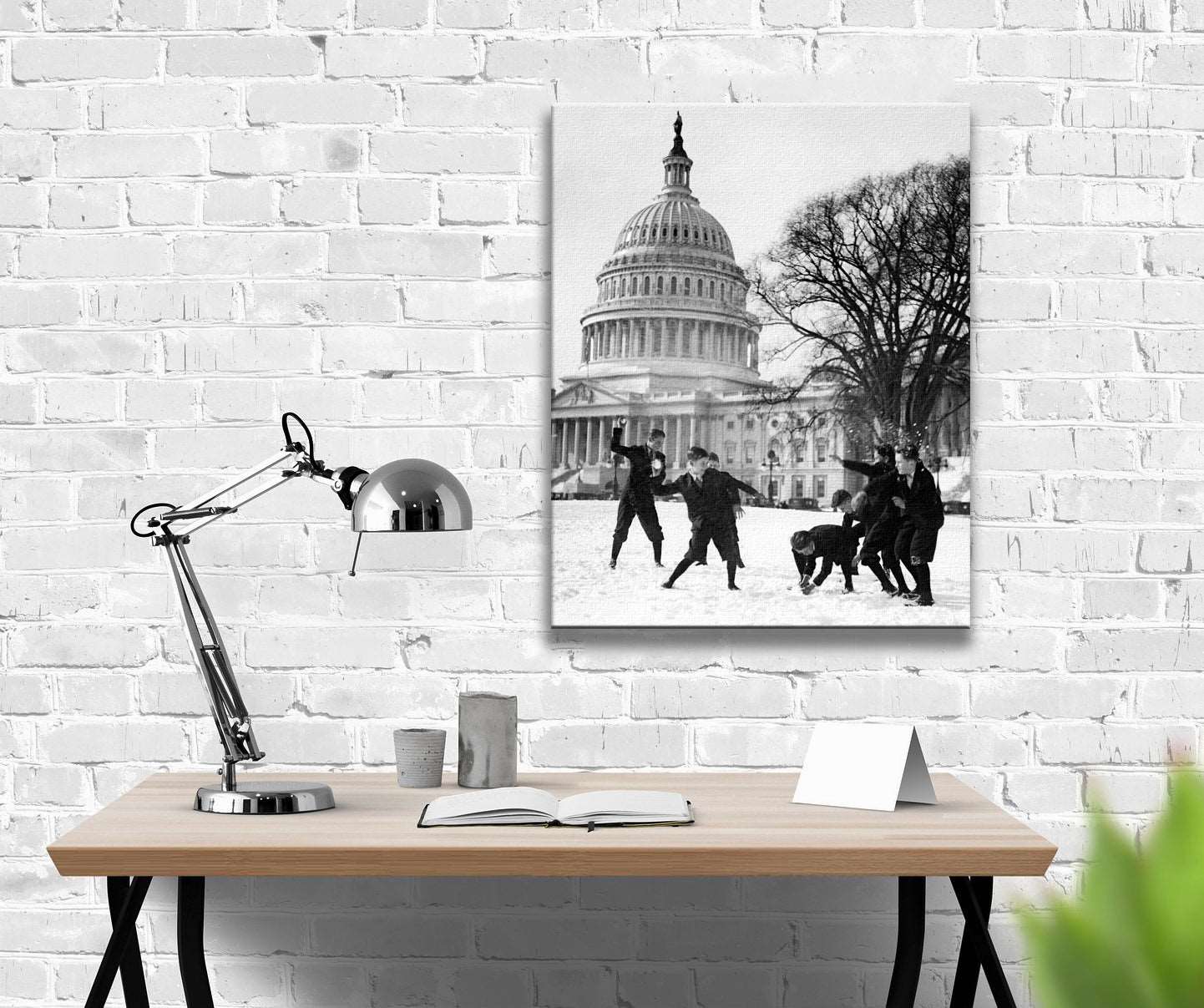 A canvas print of a black and white photo of Pages in front of the Capitol Building hanging on a white brick wall