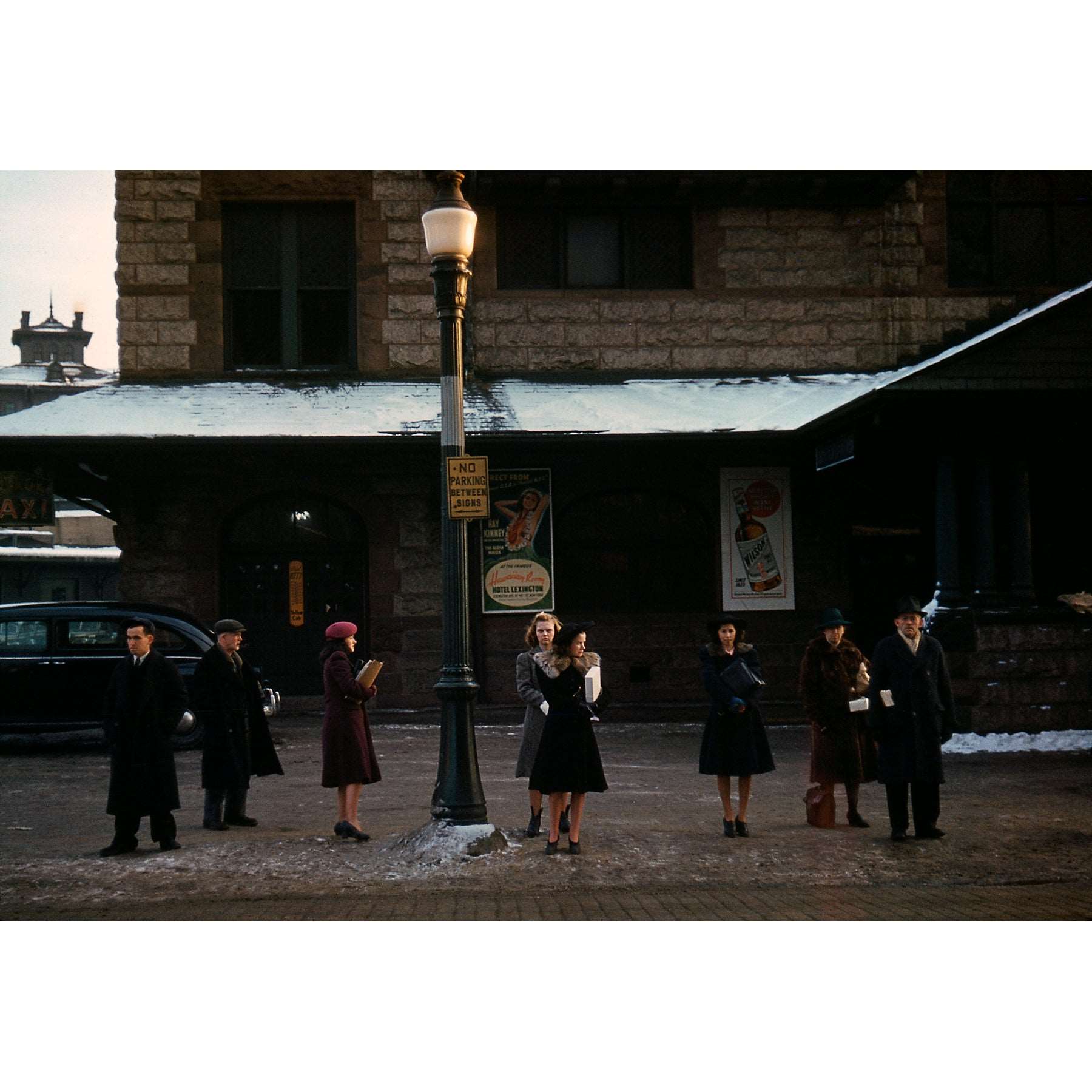 A vintage photograph of a group of commuters waiting for a bus in Lowell, Massachusetts