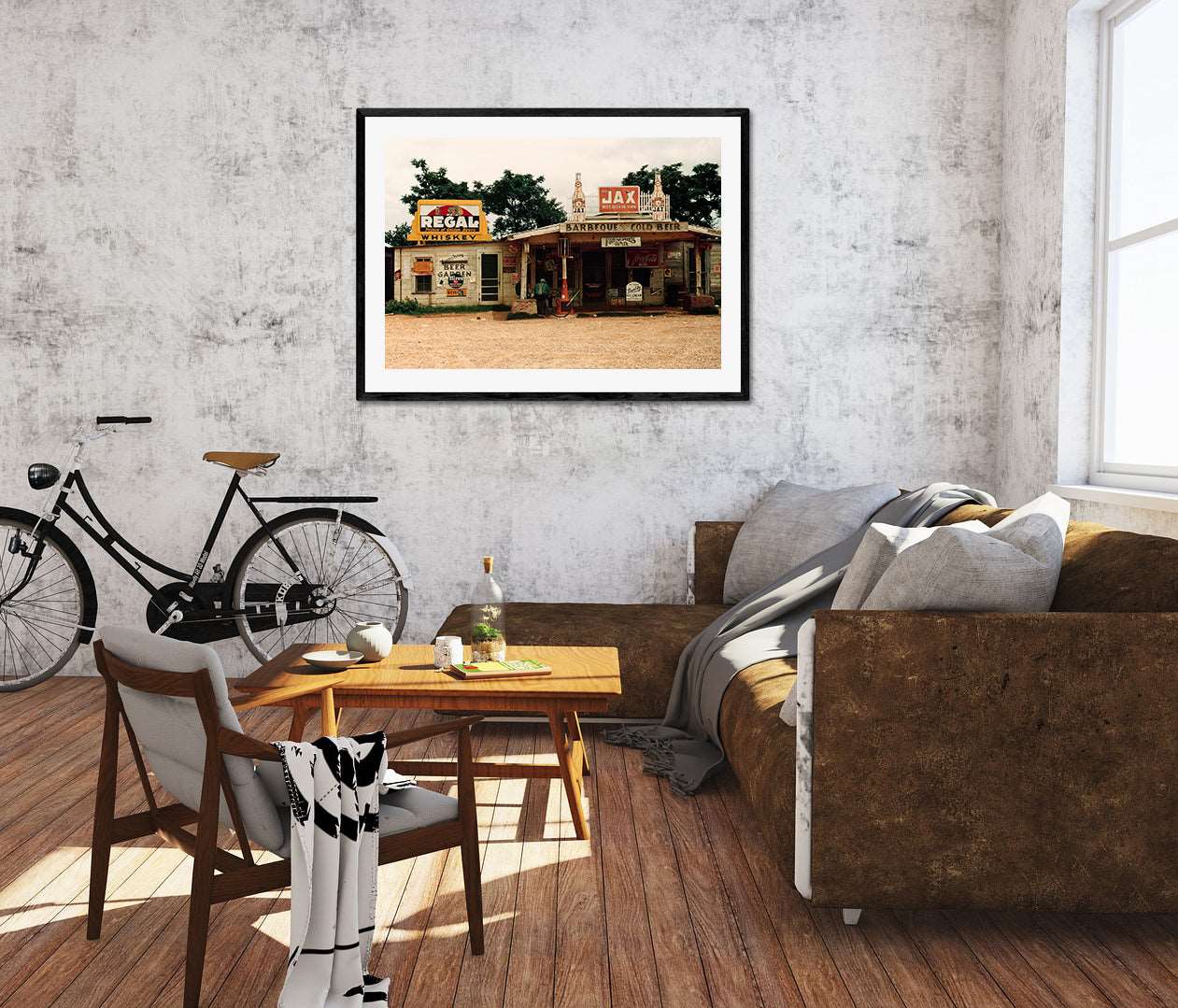 A living room with a brown couch and a framed paper print of a vintage photo of a crossroads store