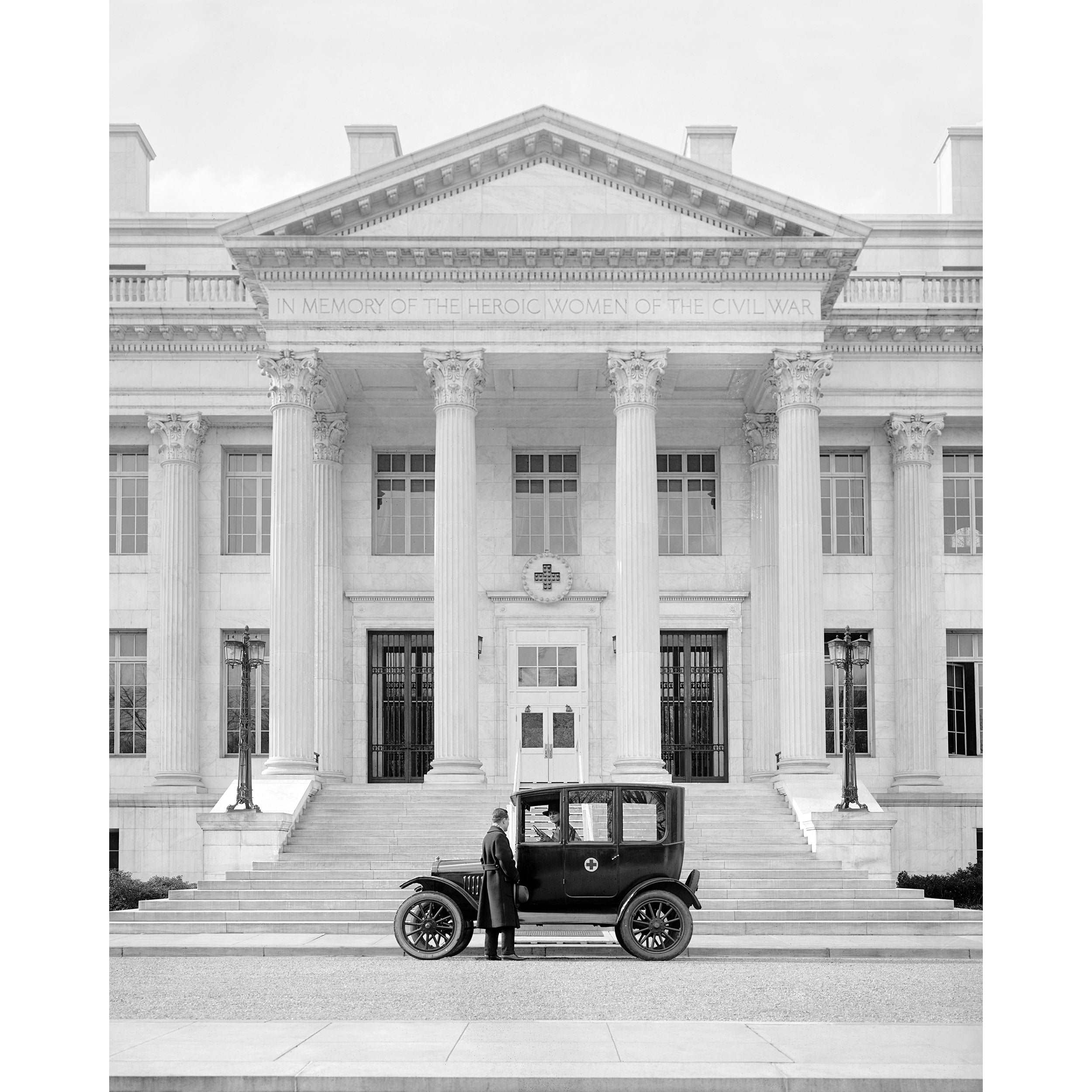 A vintage photograph of a Ford Coupe parked in front of the American Red Cross Building