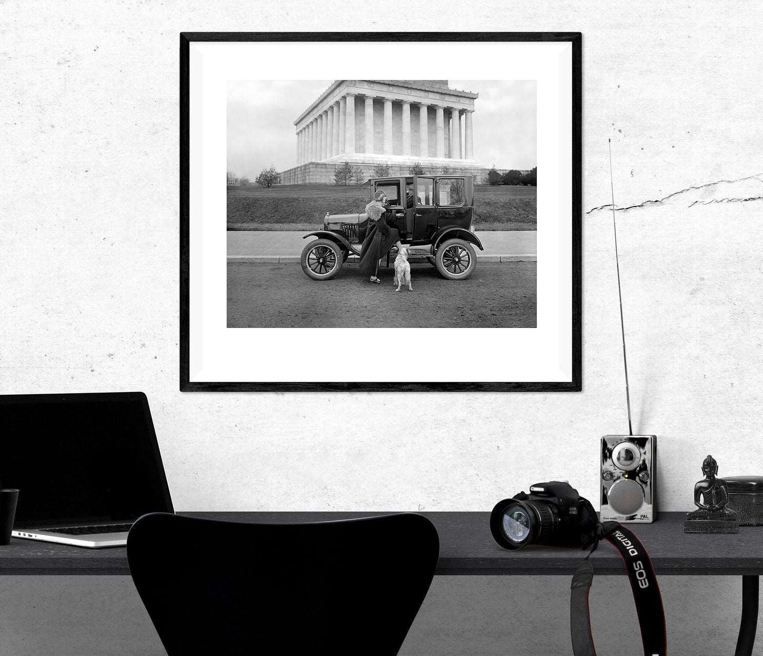 A framed print of a vintage photograph of a Ford at the Lincoln Memorial hanging on a wall above a desk