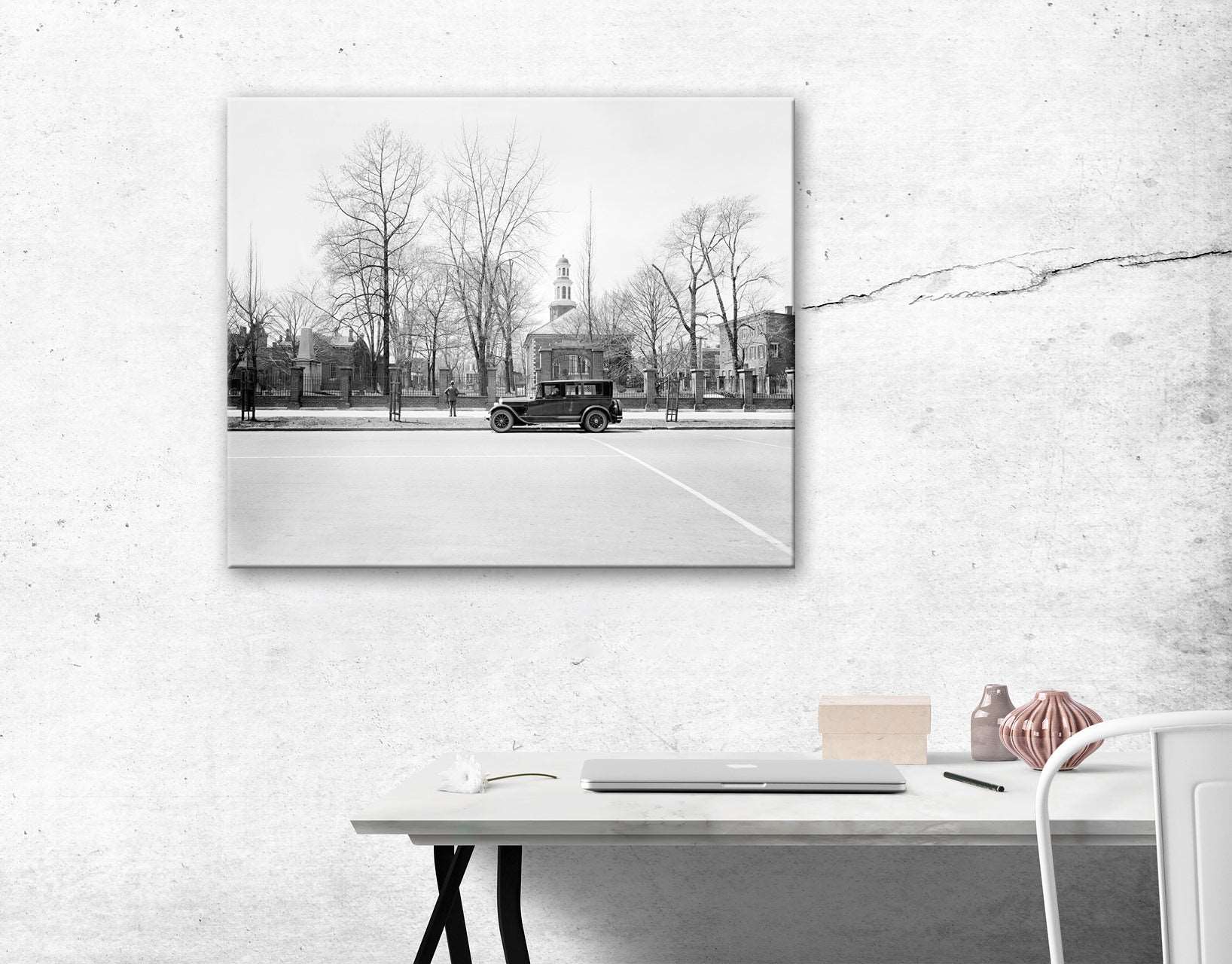 A canvas print of a vintage photograph of a Ford in front of Christ Church, hanging above a white desk