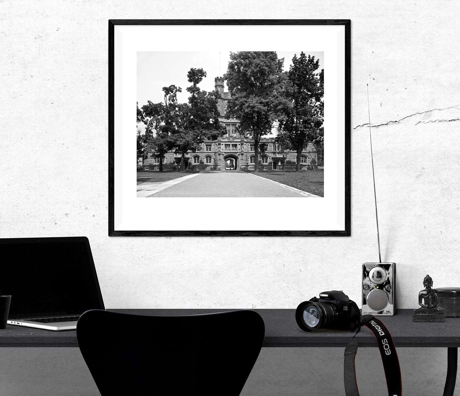 A photograph of a desk with a framed print on the wall above, featuring vintage photograph of Princeton Unviversity