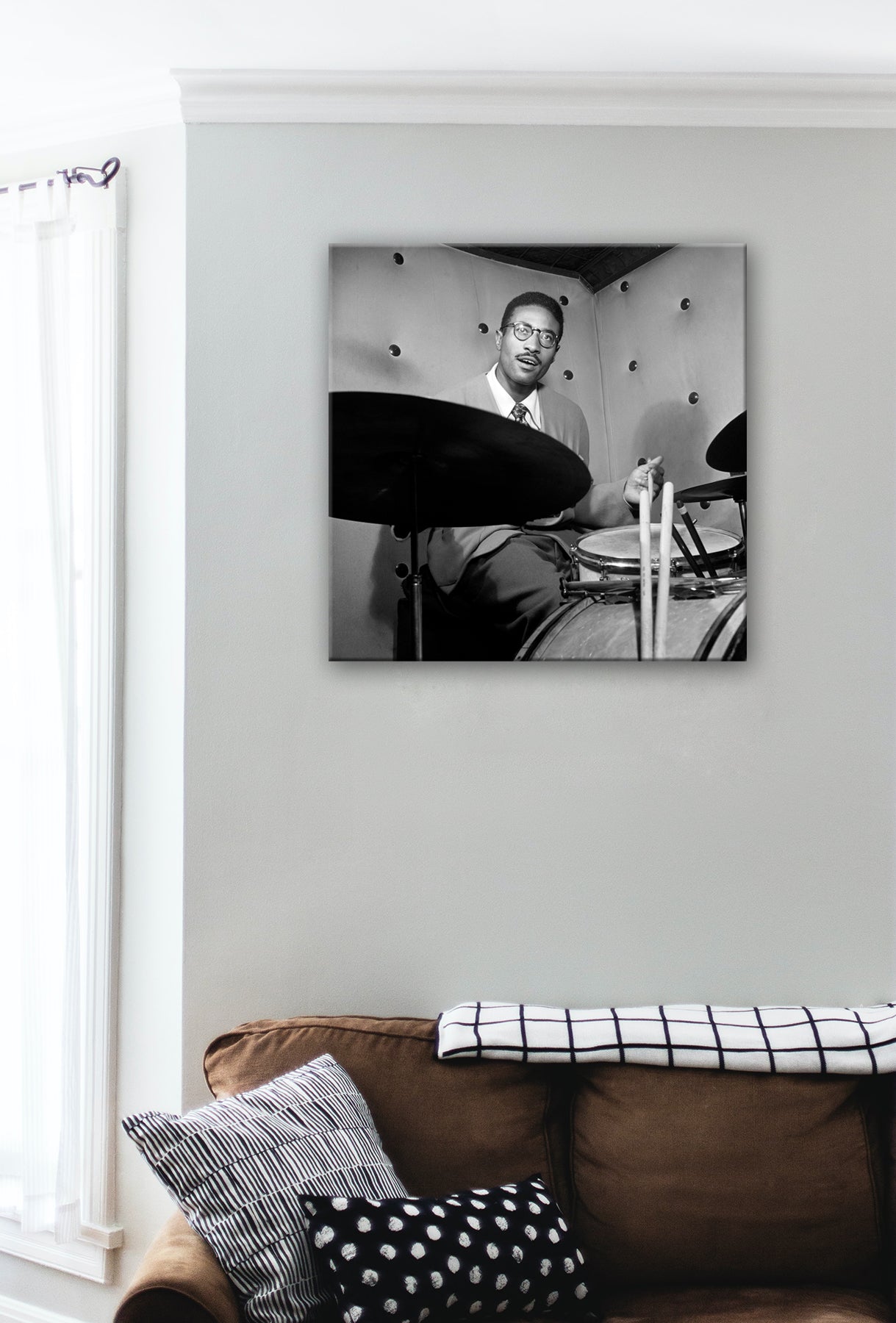 A brown couch with a stretched canvas print hanging above, featuring a photo of Max Roach
