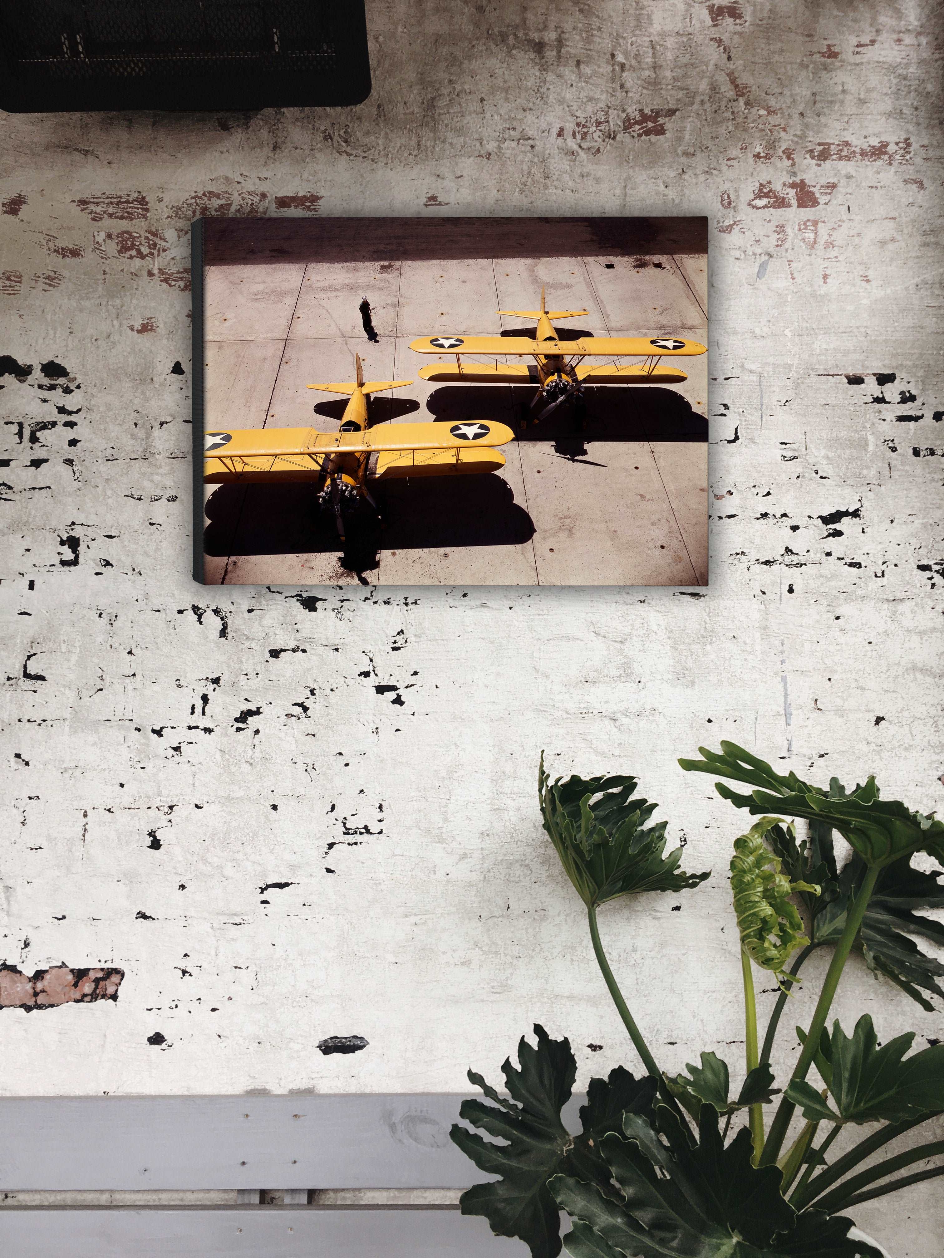 A rustic brick wall with a canvas print of a photograph of Navy N2S Planes