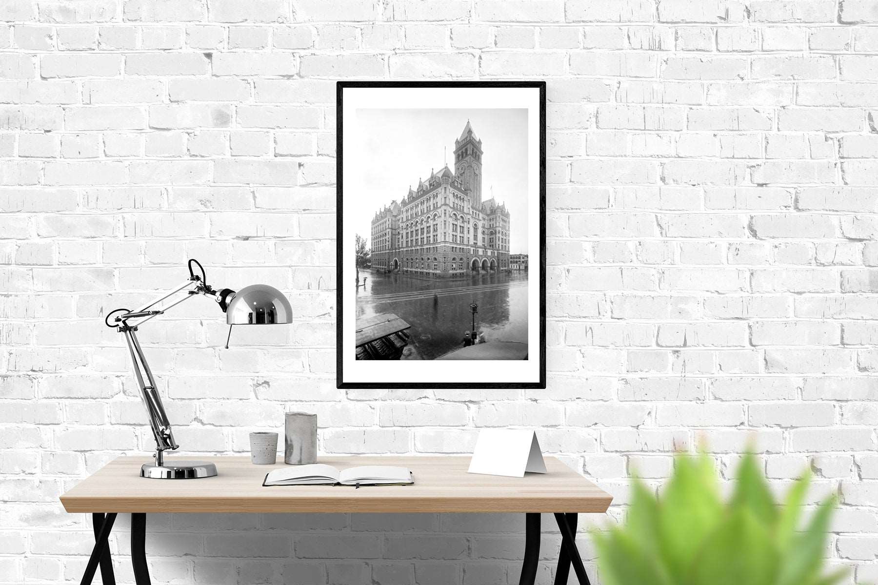 A photo of a desk in an office, with a framed paper print on the wall, featuring a photograph of Washington DC
