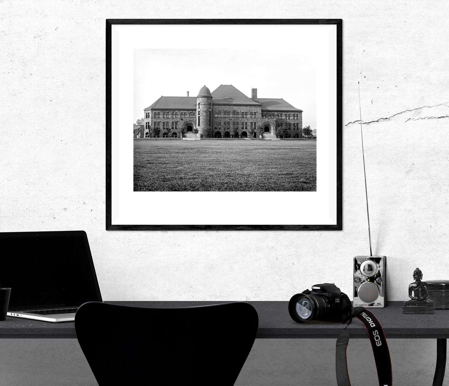 A framed paper print of a photograph of University of Minnesota's Pillsbury Hall hanging on a wall above a desk