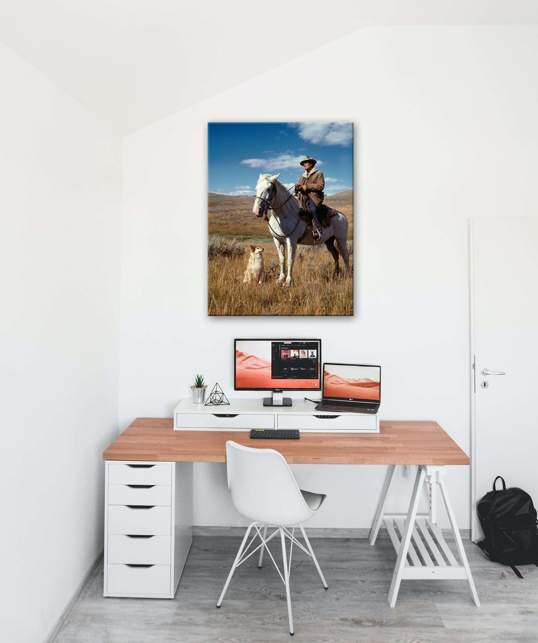 A photograph of an office with a canvas print of a photograph of a man on a horse hanging above the desk