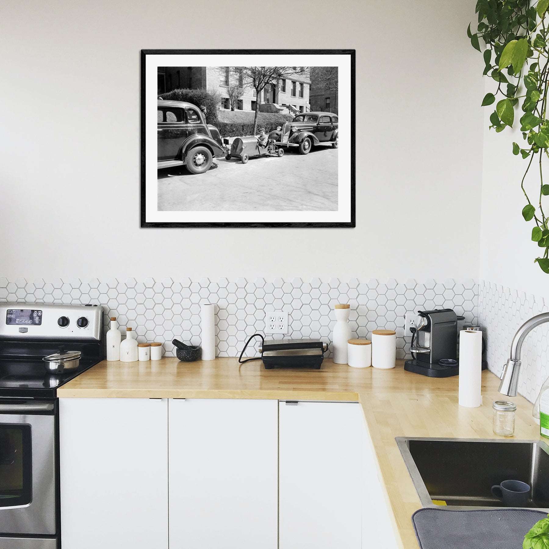 A modern kitchen with a framed paper print of a boy in Washington DC parking his miniature car