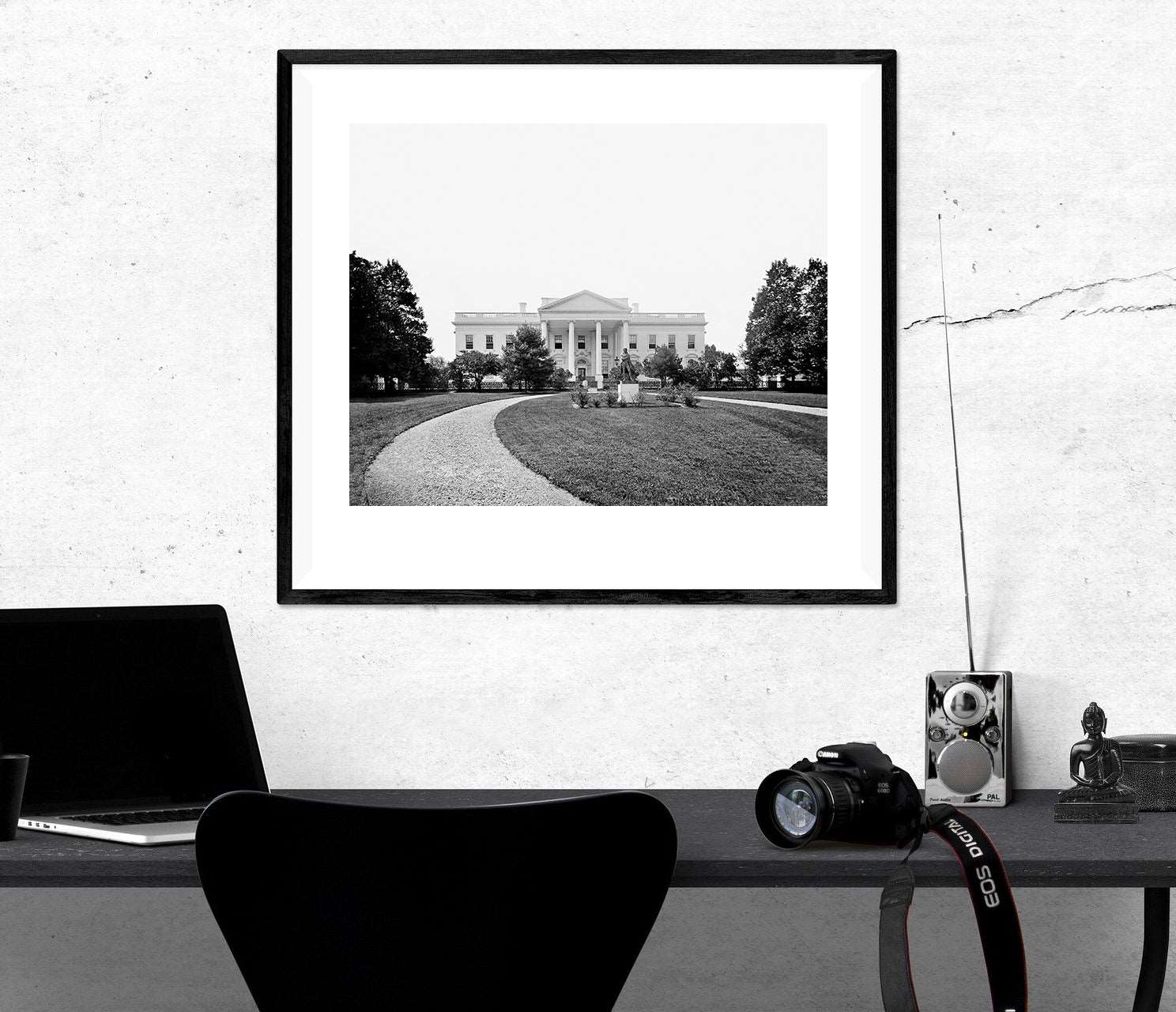 A framed paper print of a vintage photograph of the White House hanging on a white wall