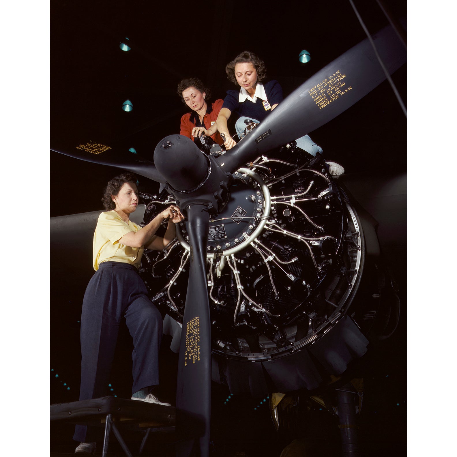 A full color vintage photograph from the 1940s depicting several women working on a C-47 Douglas Cargo Transport Plane