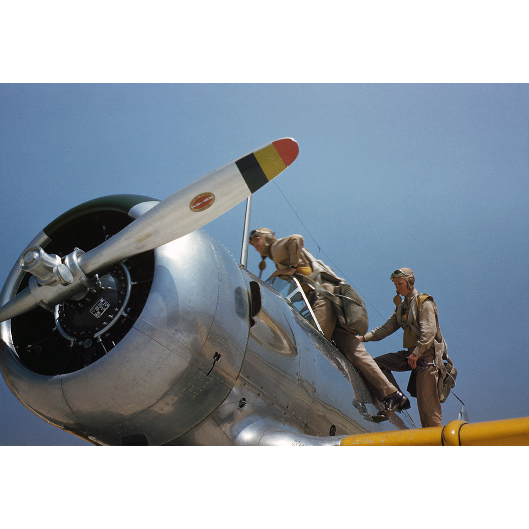Two people on a vintage airplane with a clear blue sky background