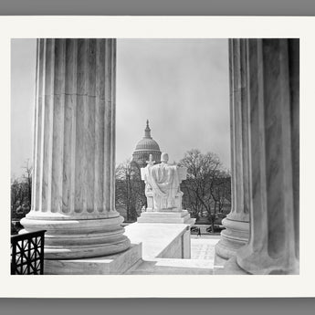 A mockup of a paper print of a vintage image of the US Capitol viewed from between columns of the Supreme Court Building