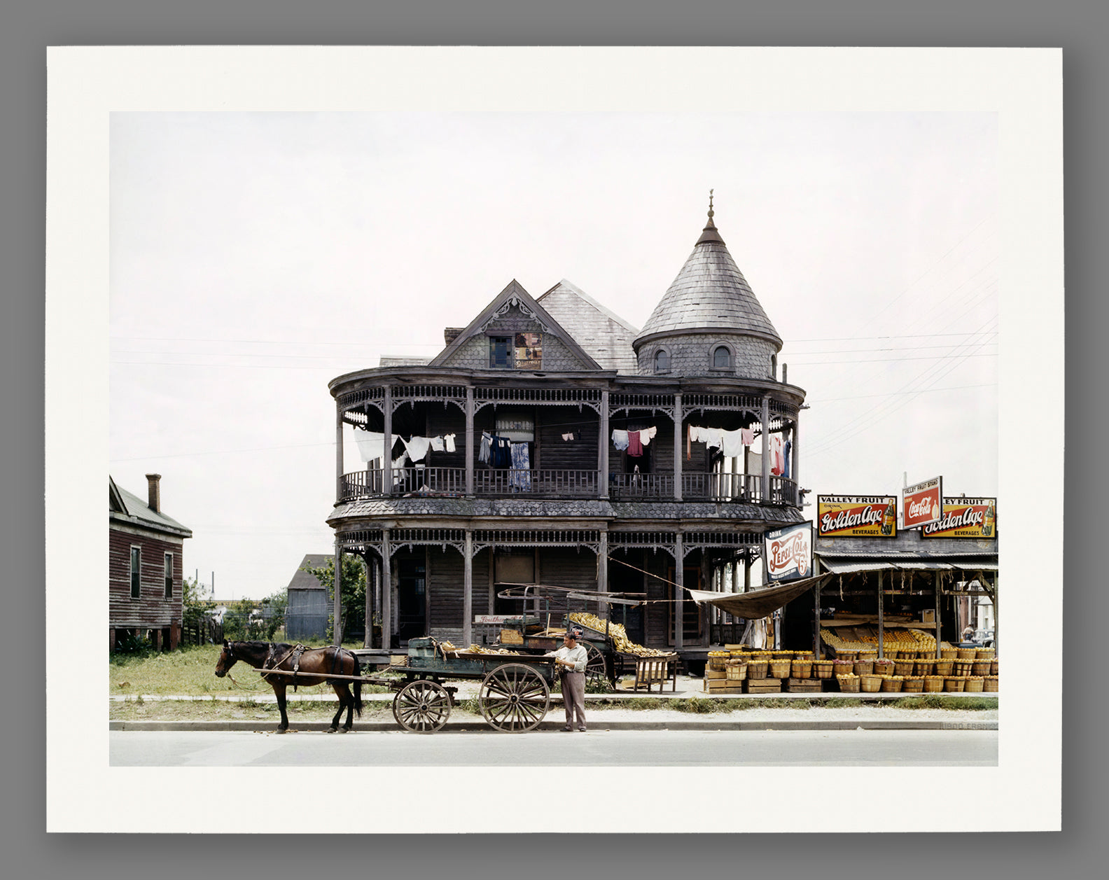 A mockup paper print of a restored vintage photograph of a house in Houston, Texas with a horse and produce stand