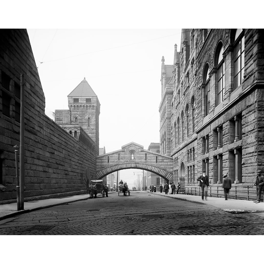 A vintage photograph of a Pittsburgh street with an arched stone bridge in the center