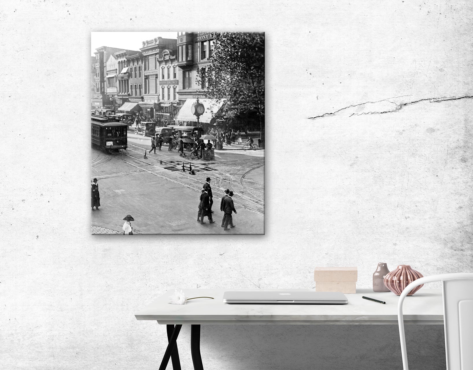 A canvas print of a vintage photograph hanging on a white wall above a desk