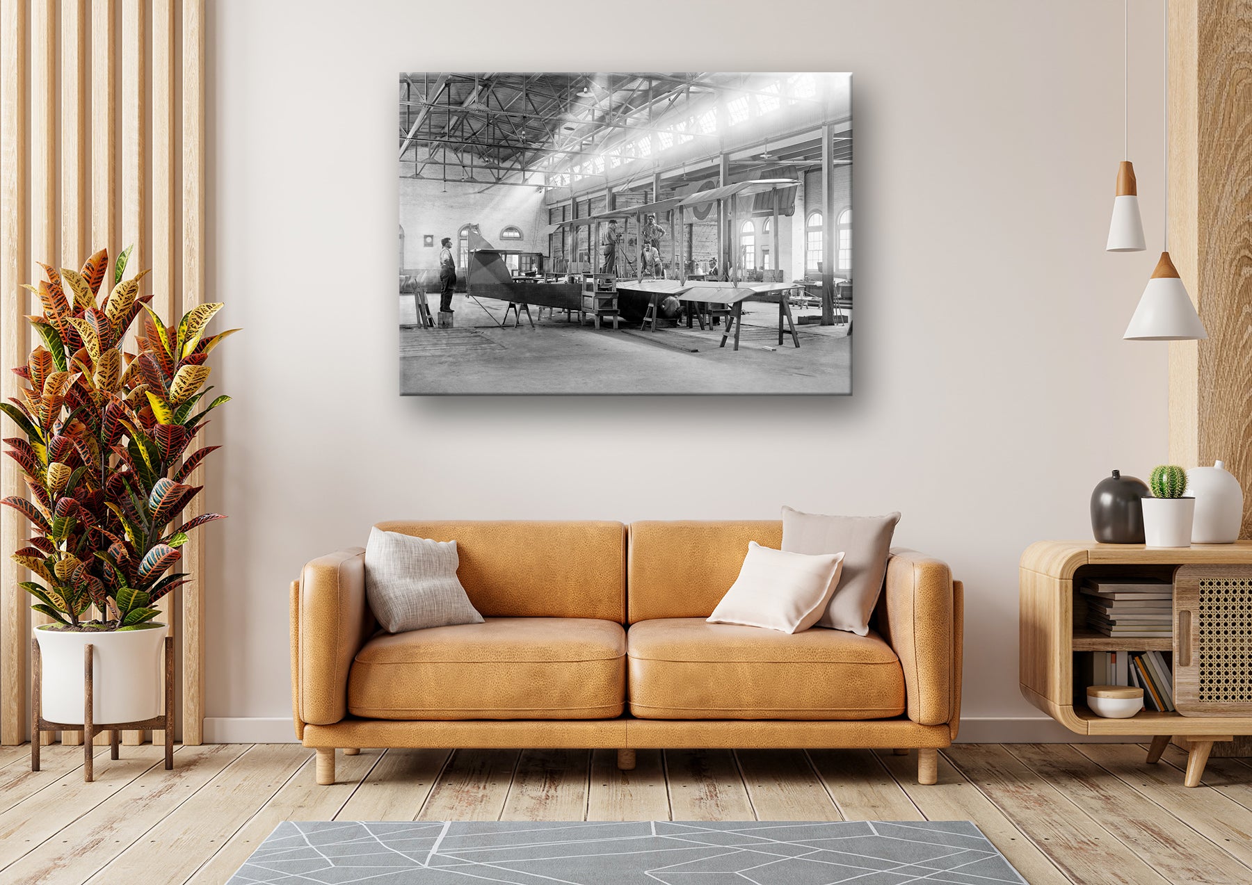 A stretched canvas print of a vintage photograph of an airplane factory hanging in a living room