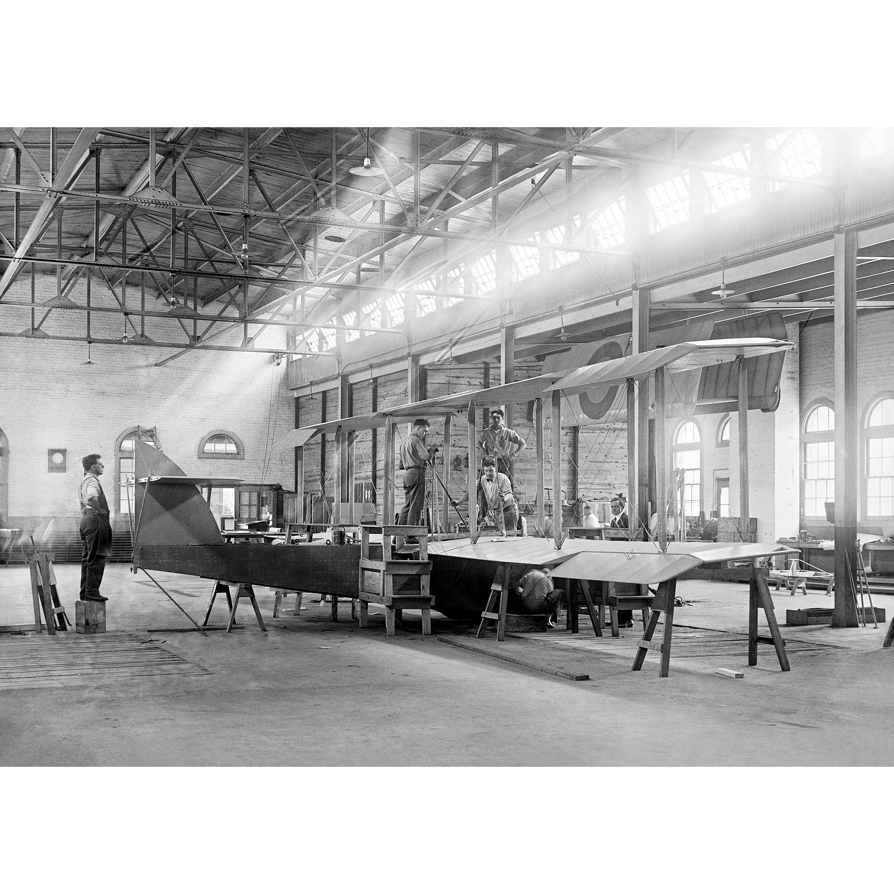 A vintage photograph of several men working in an airplane factoy in Alexandria