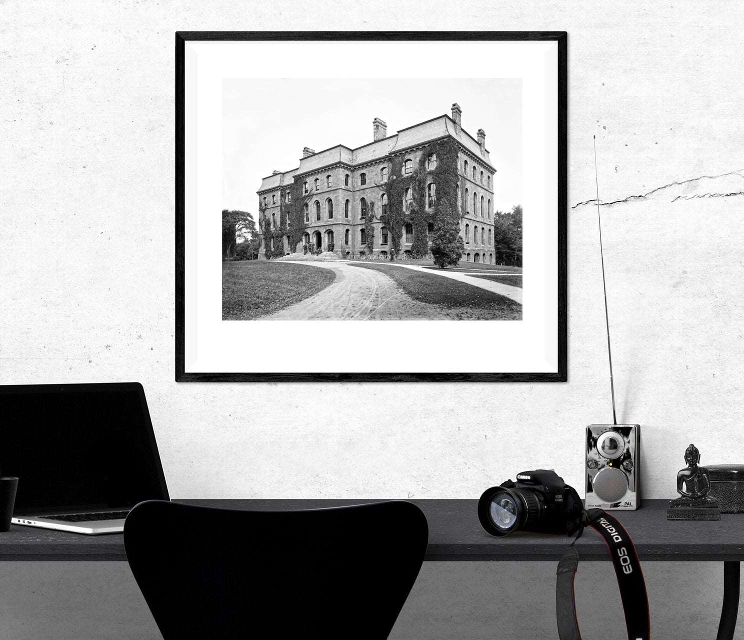 A black desk with a framed print hanging above it, featuring a photograph of Anderson Hall