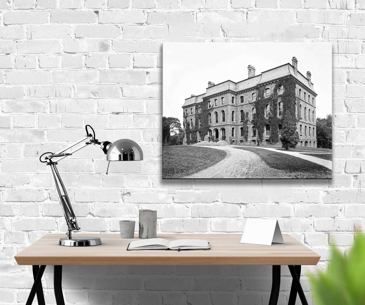 A canvas print hanging on a brick wall, featuring a vintage photograph of the University of Rochester