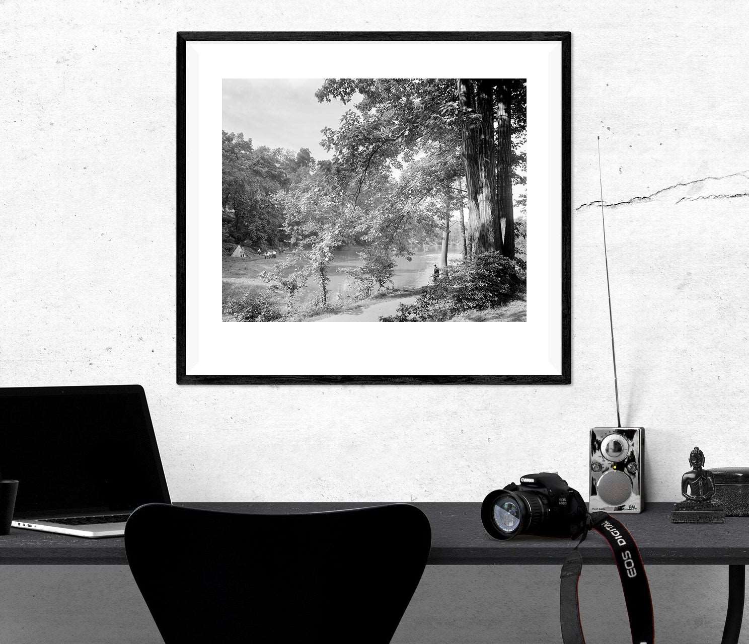 A framed paper print hanging above a black desk, featuring a vintage photograph of Chamounix Lake