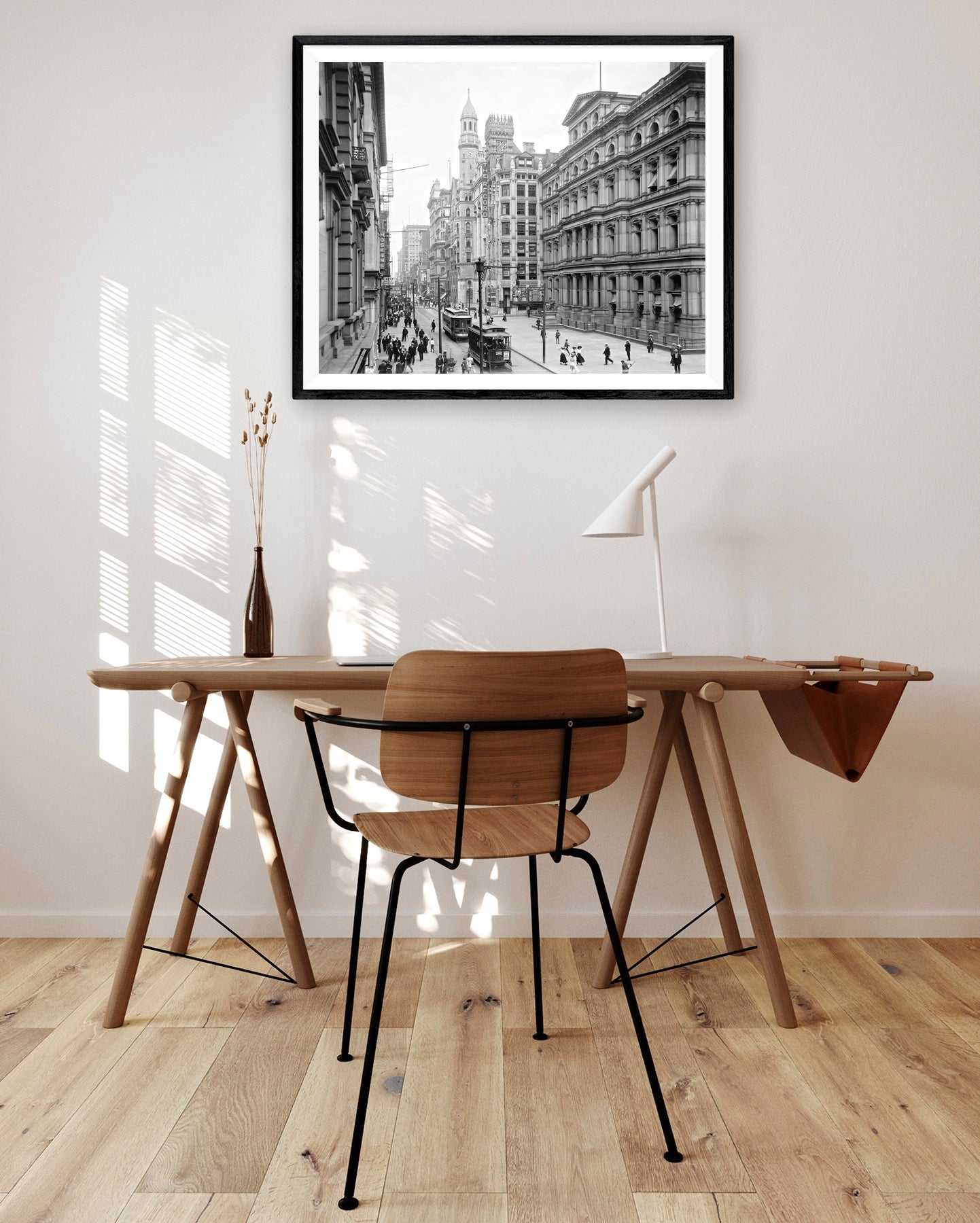 A framed paper print hanging above a brown desk and chair