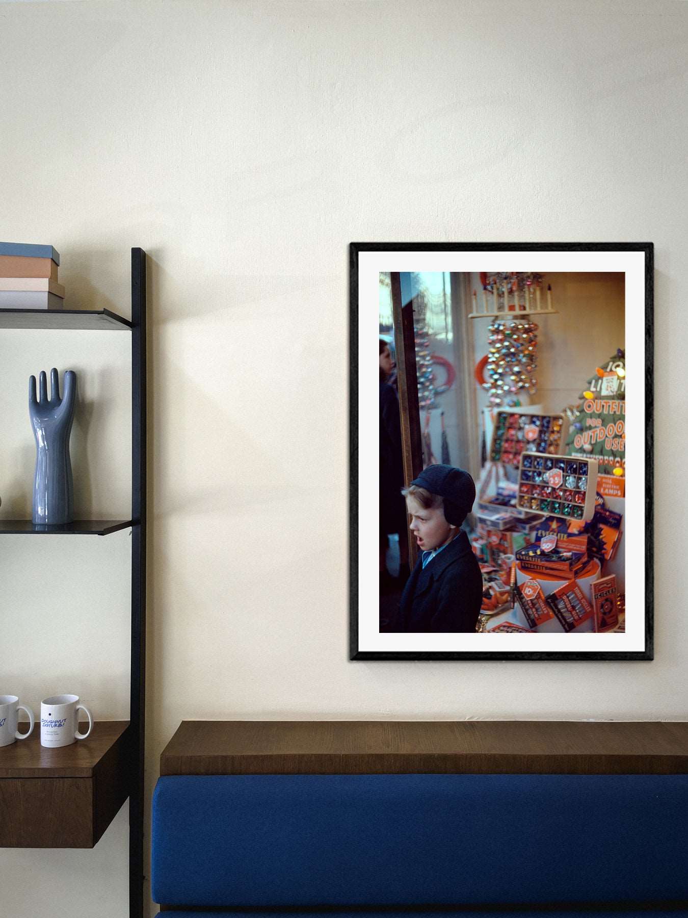 A framed paper print of a vintage photograph of a Christmas display hangs in a modern room