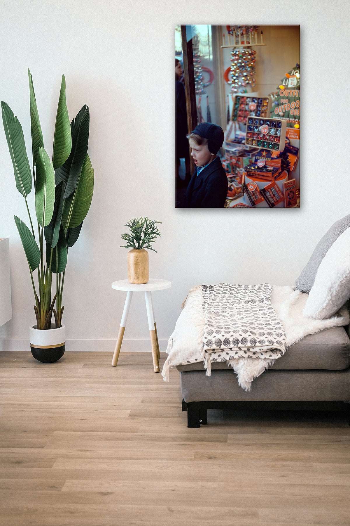 A canvas print of a vintage, color photograph hanging next to a plant in a living room