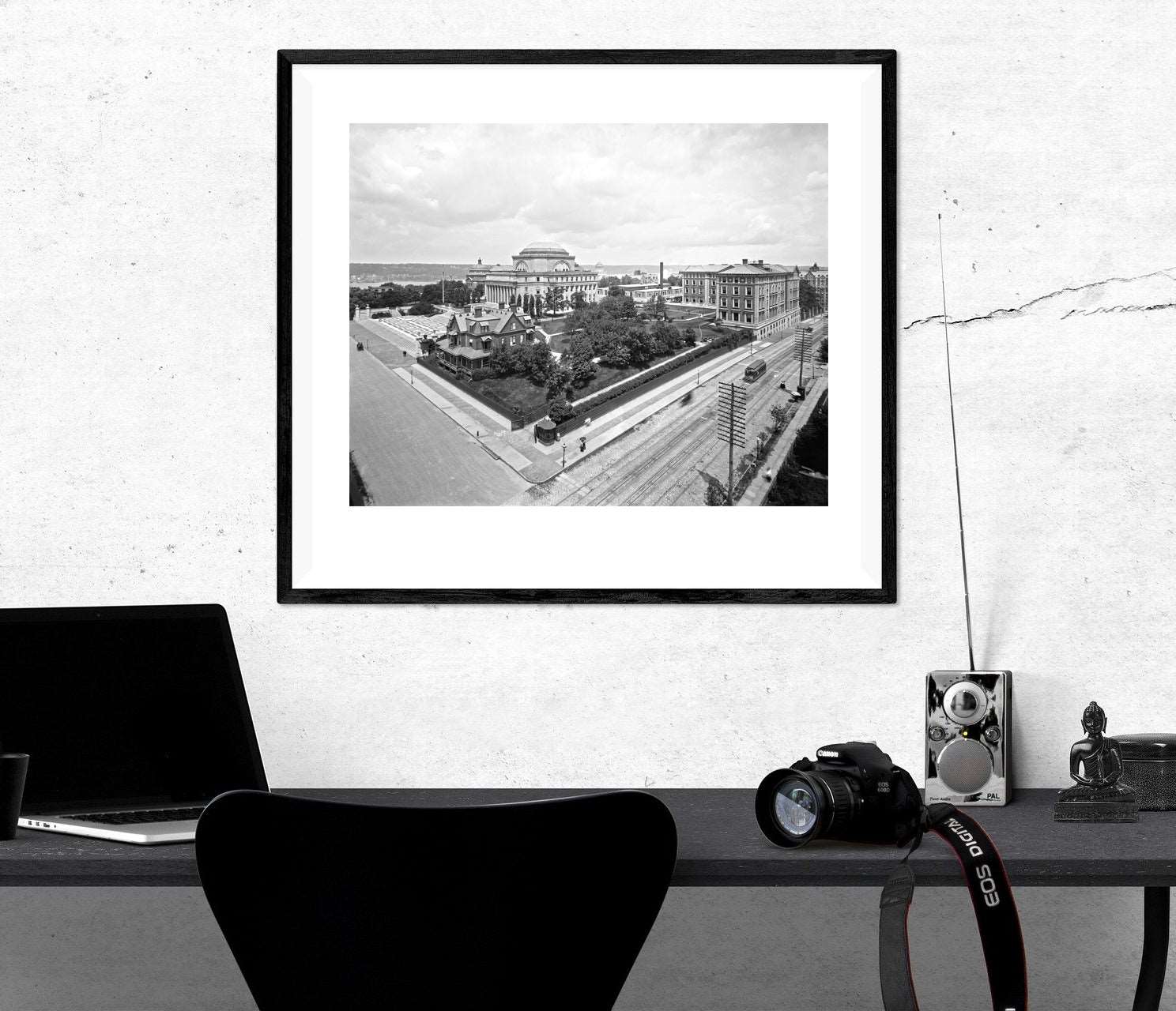 A framed paper print of a vintage photograph of Columbia University hanging above a desk