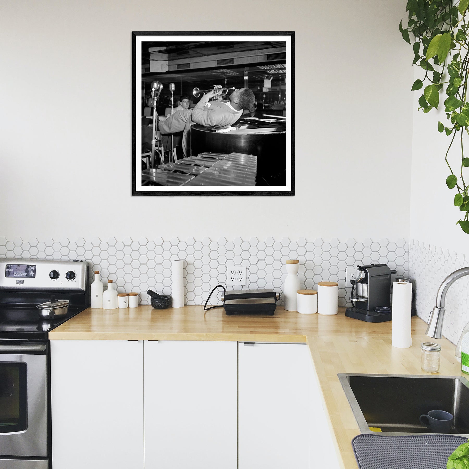 A framed paper print hanging in a kitchen, displaying a photograph of Dizzy Gillespie
