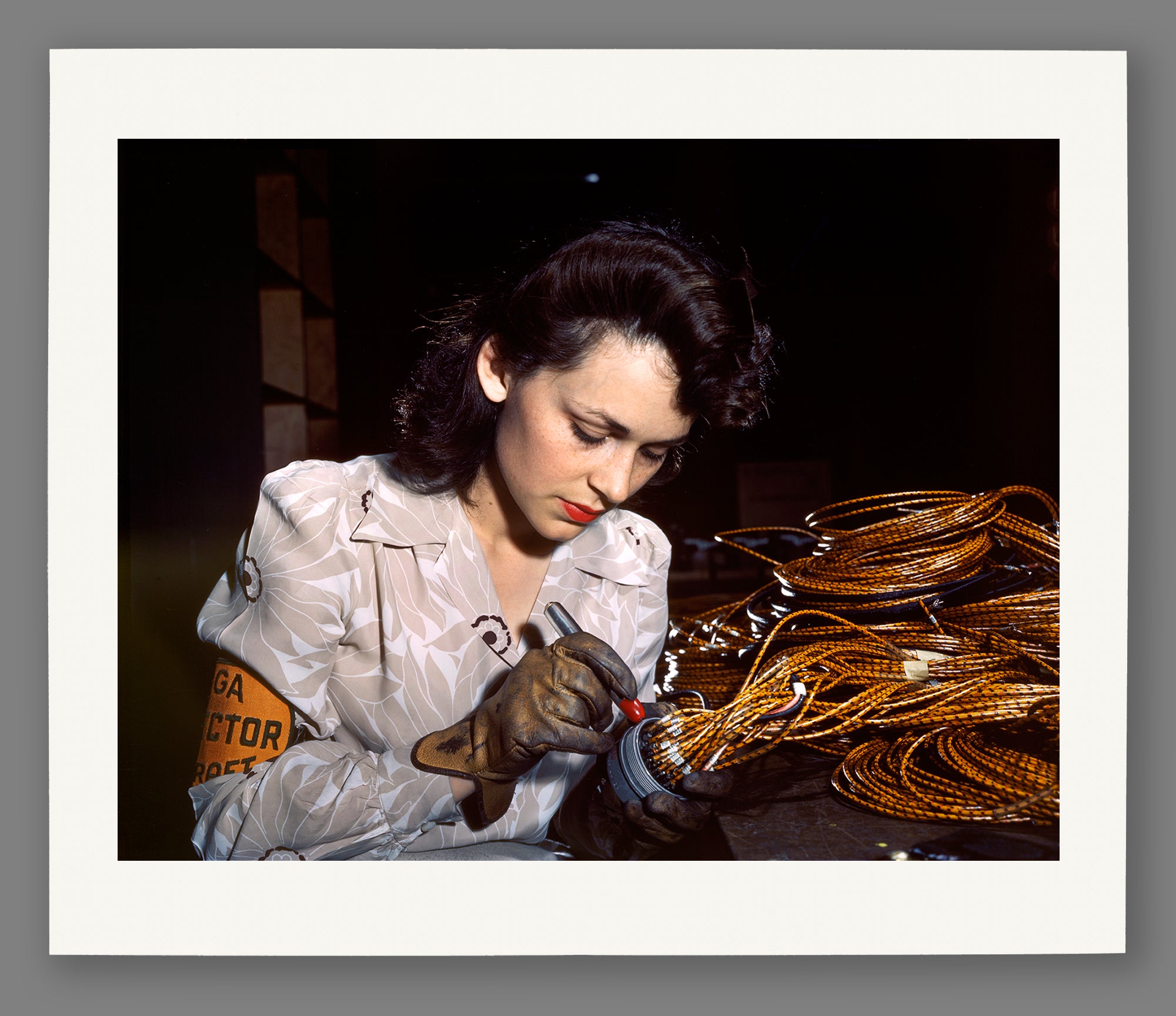 A reproduction print on paper of a vintage photograph of a female aircraft worker