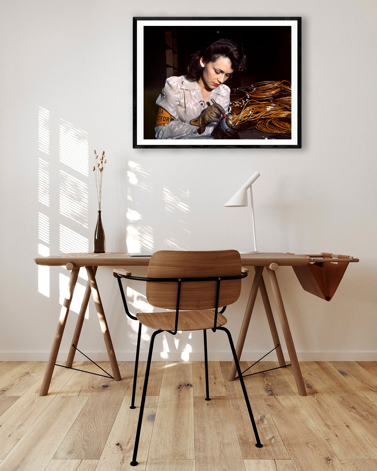 A digital image showing a framed paper print of vintage photograph hanging on a wall above a table