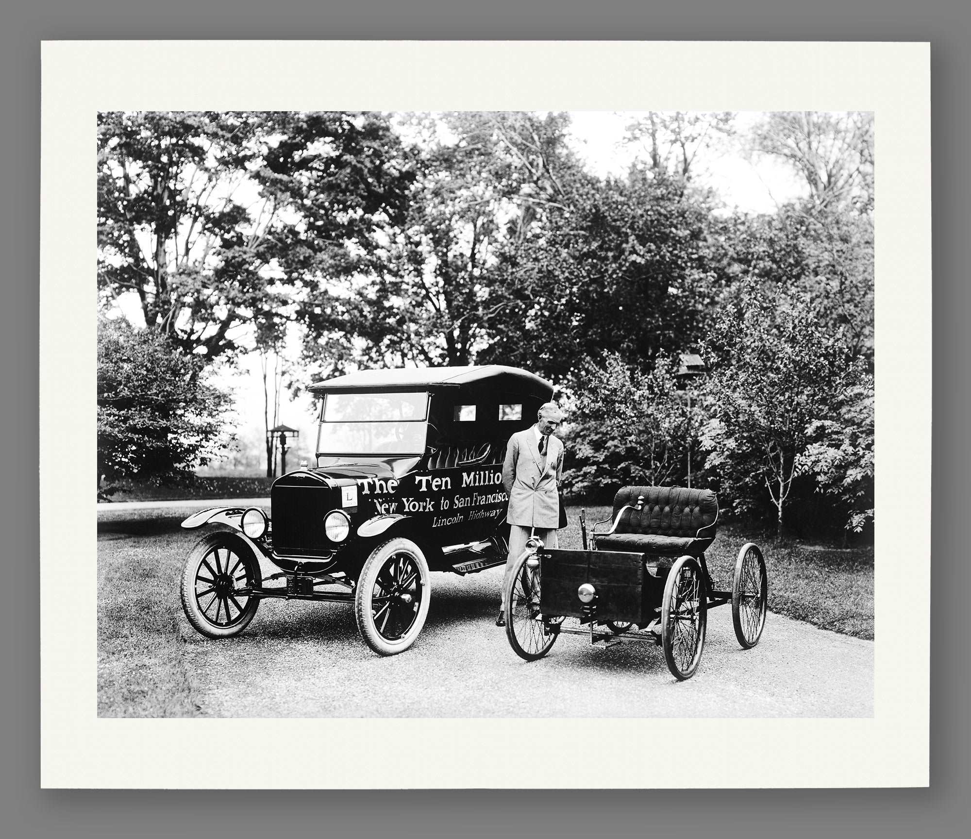 A paper reproduction print of a photogrpah of Henry Ford with the first and ten millionth Fords