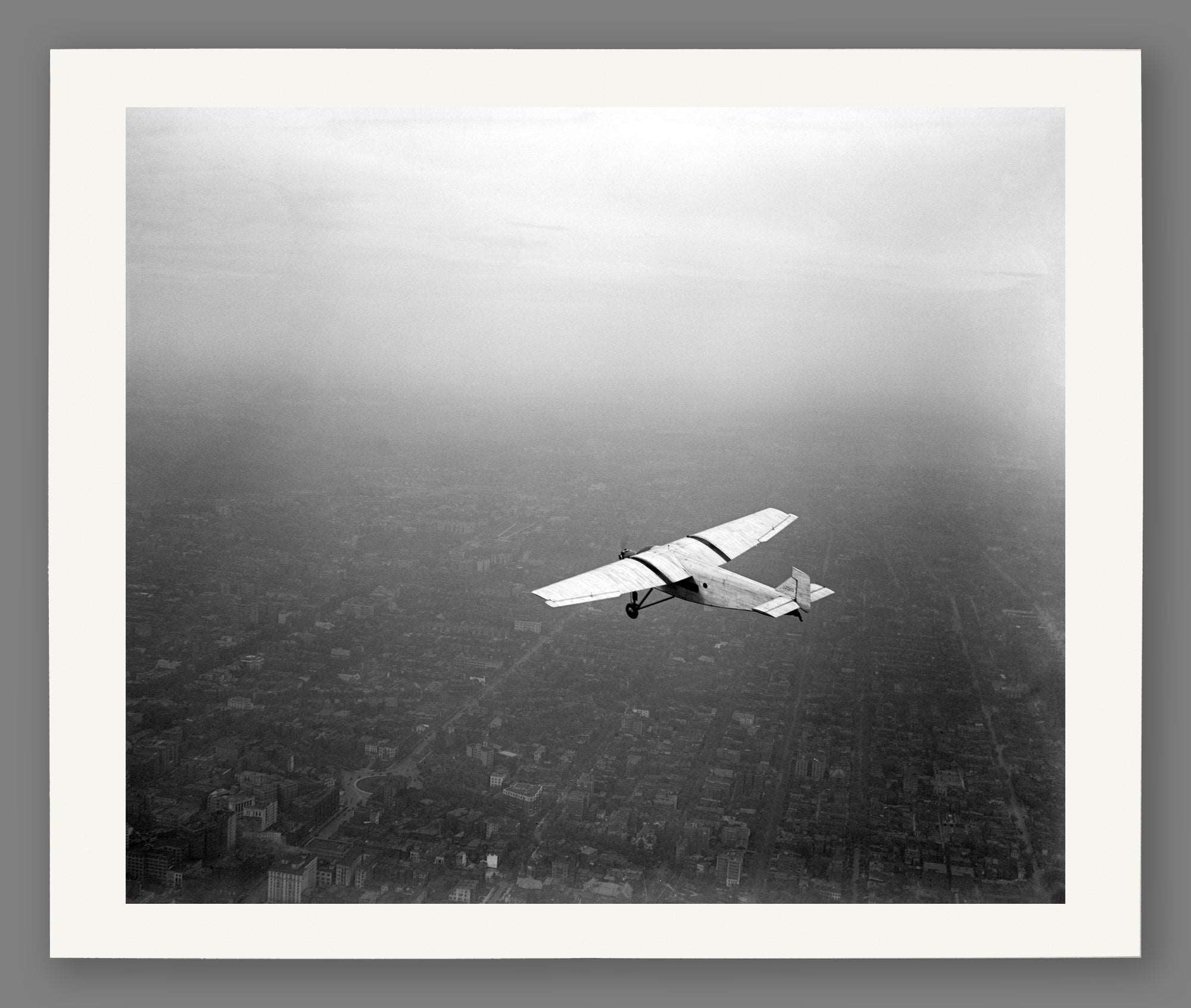 A fine art paper print featuring a vintage photograph of a Ford plane in flight