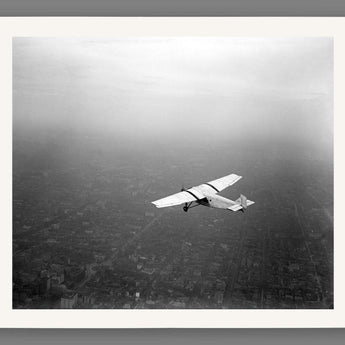 A fine art paper print featuring a vintage photograph of a Ford plane in flight