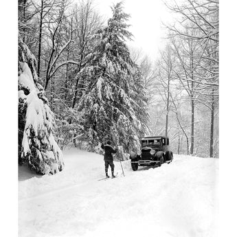 A vintage photograph of a Ford Motor Company vehicle being guided through the snow
