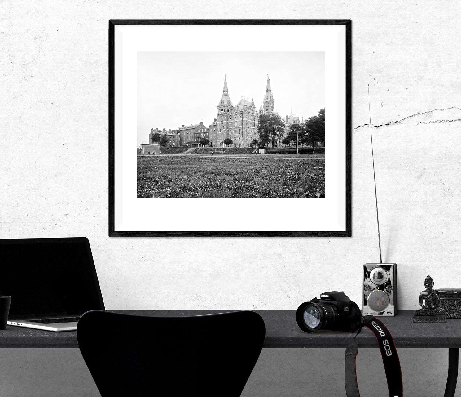 A framed paper print of a vintage photograph hanging on a wall above a desk