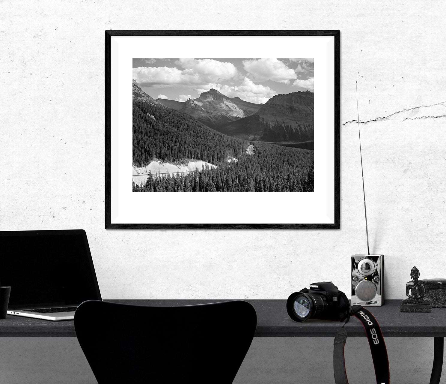 A framed paper print of a vintage photograph of Glacier National park hanging above a desk