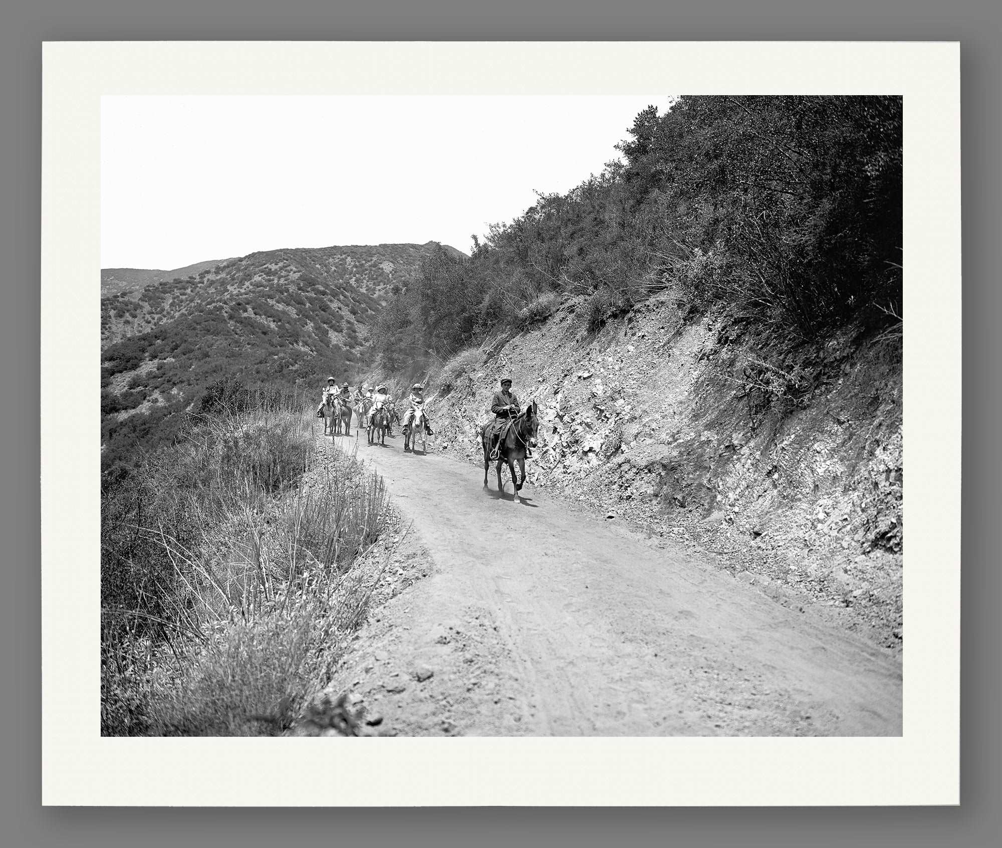 A fine art paper print of vintage photography of a group on horseback on a trail