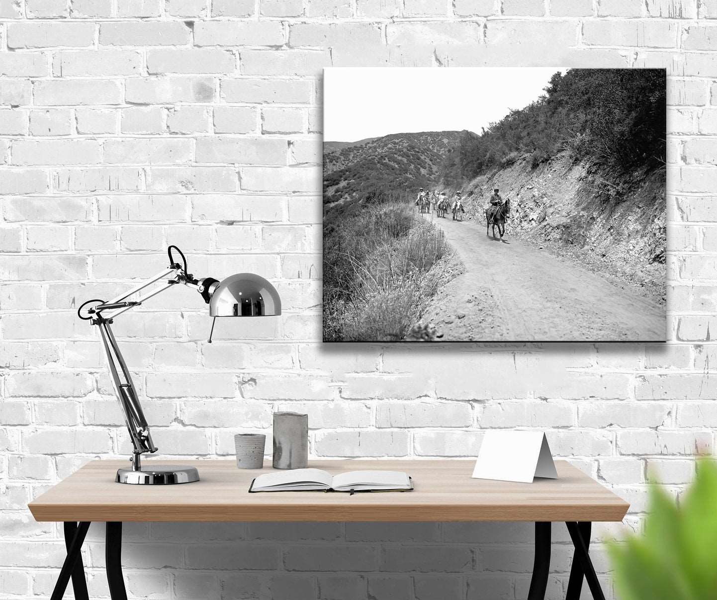 An office with a white brick wall and a canvas print of vintage photography