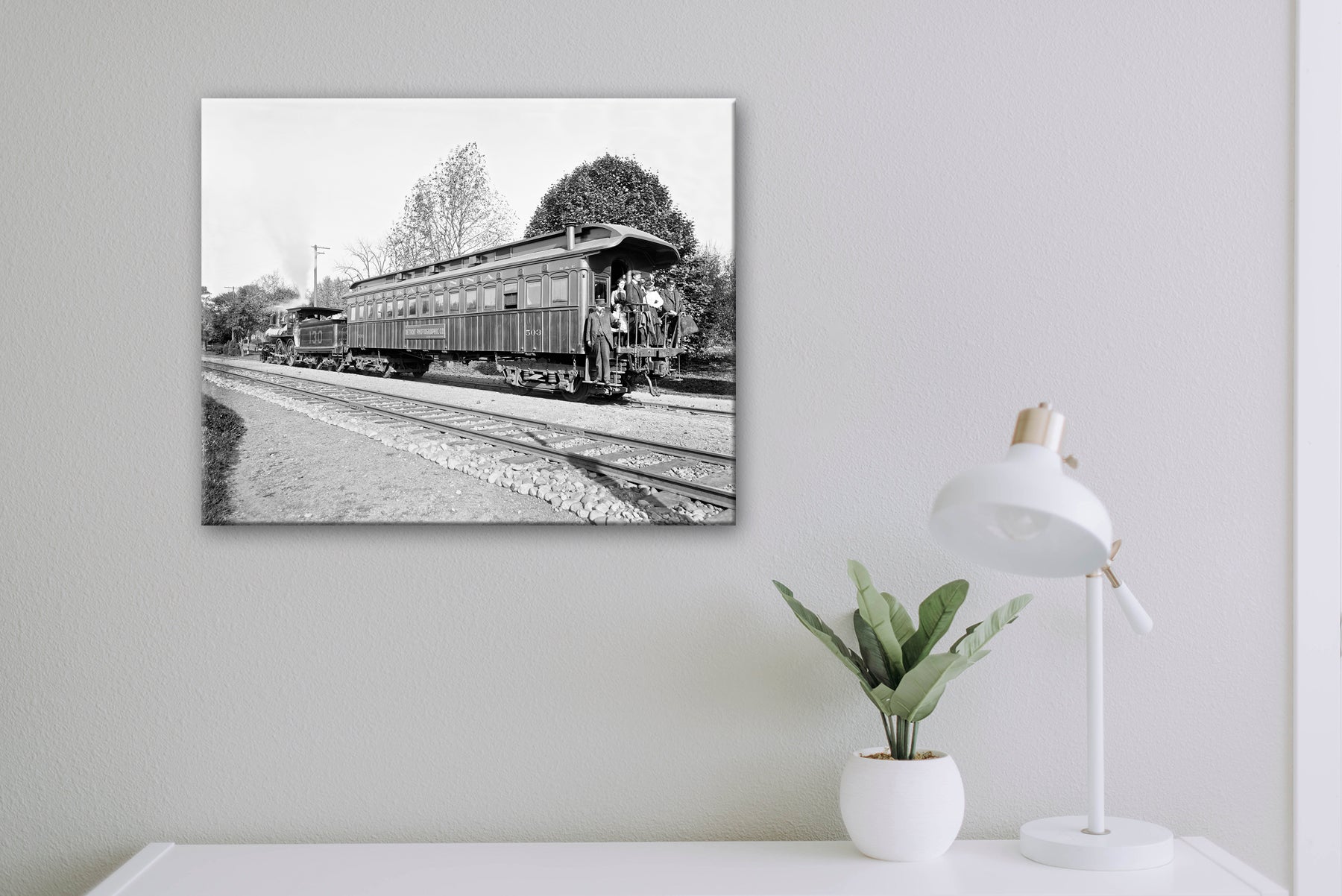 A canvas print of a vintage photograph hanging above a white desk with white decorations