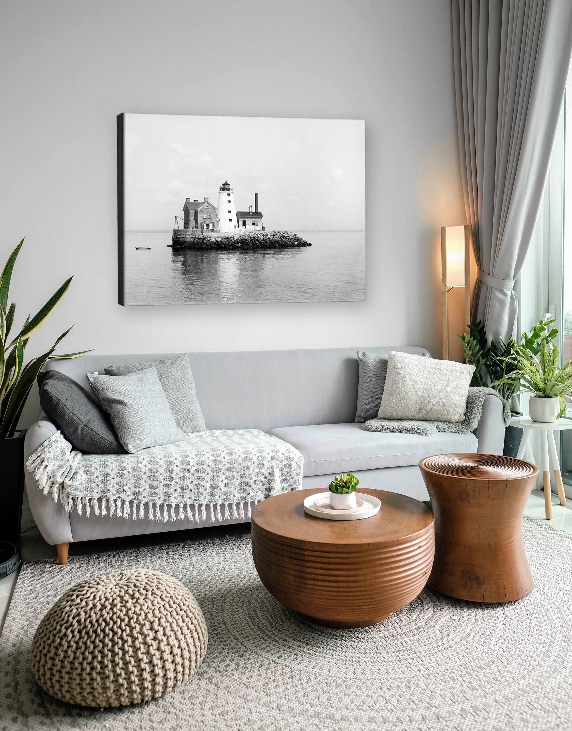 A photograph of a living room with a canvas print on the wall, featuring a photograph of a lighthouse on an island