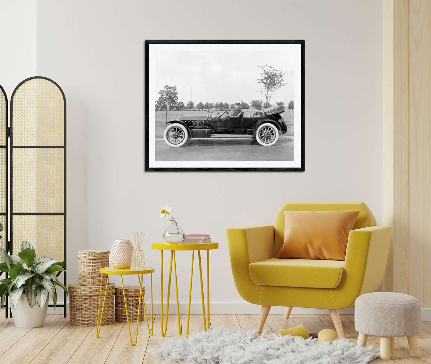 A photograph of a bright room with a framed paper print of a vintage vehicle on the wall
