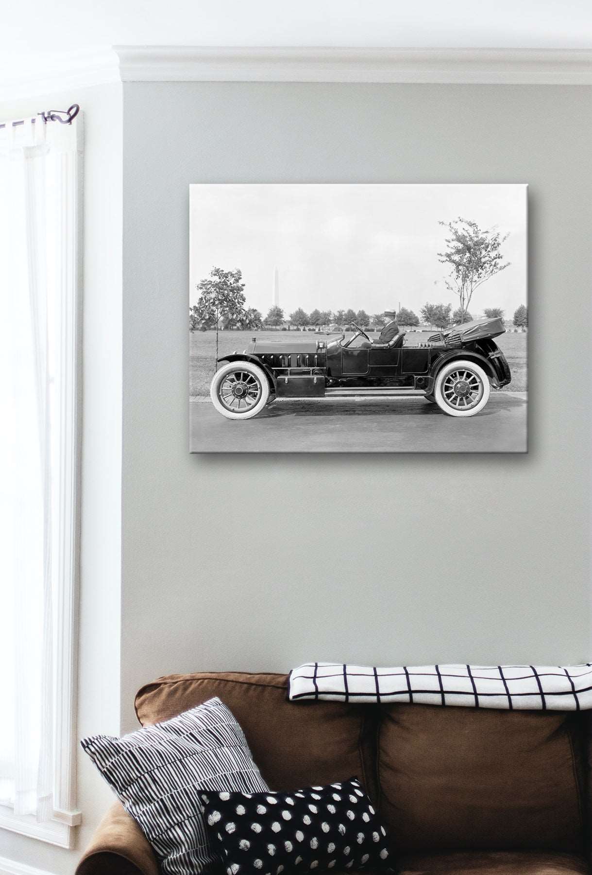 A photo of a living room with a canvas print on the wall, featuring a vintage photo of Marmon Motor Company Car