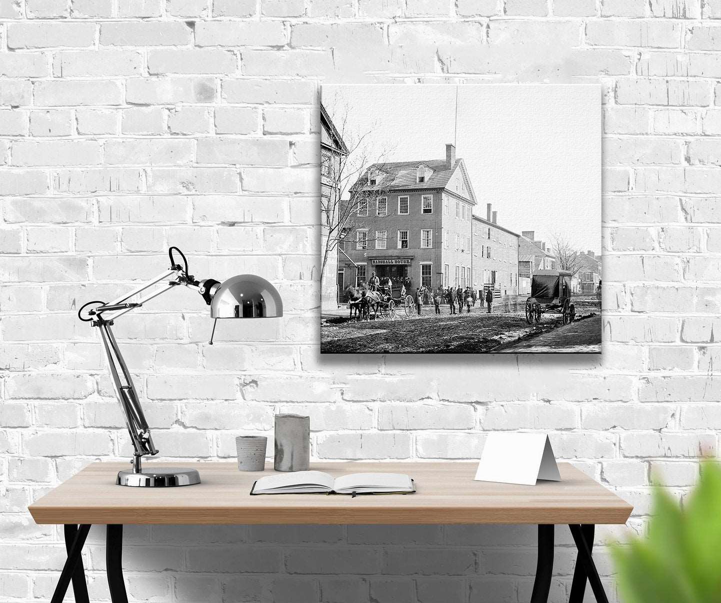 A photo of a desk in front of a white brick wall with a canvas print of a photograph of Old Town Alexandria