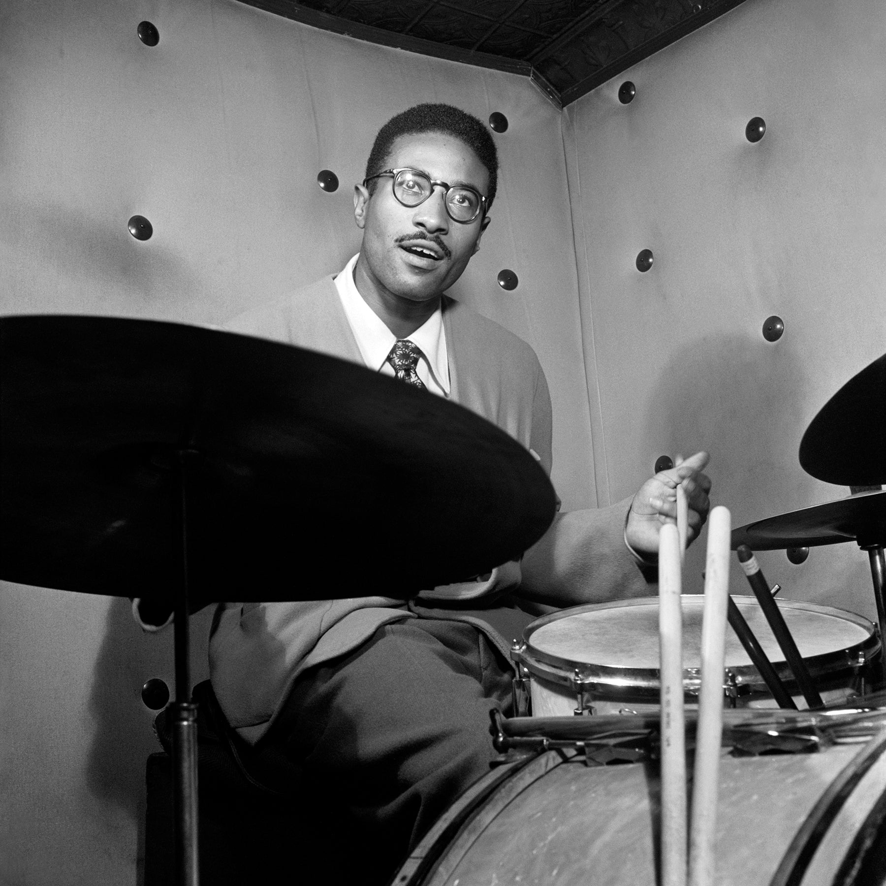 A vintage, square format photograph of Max Roach playing drums